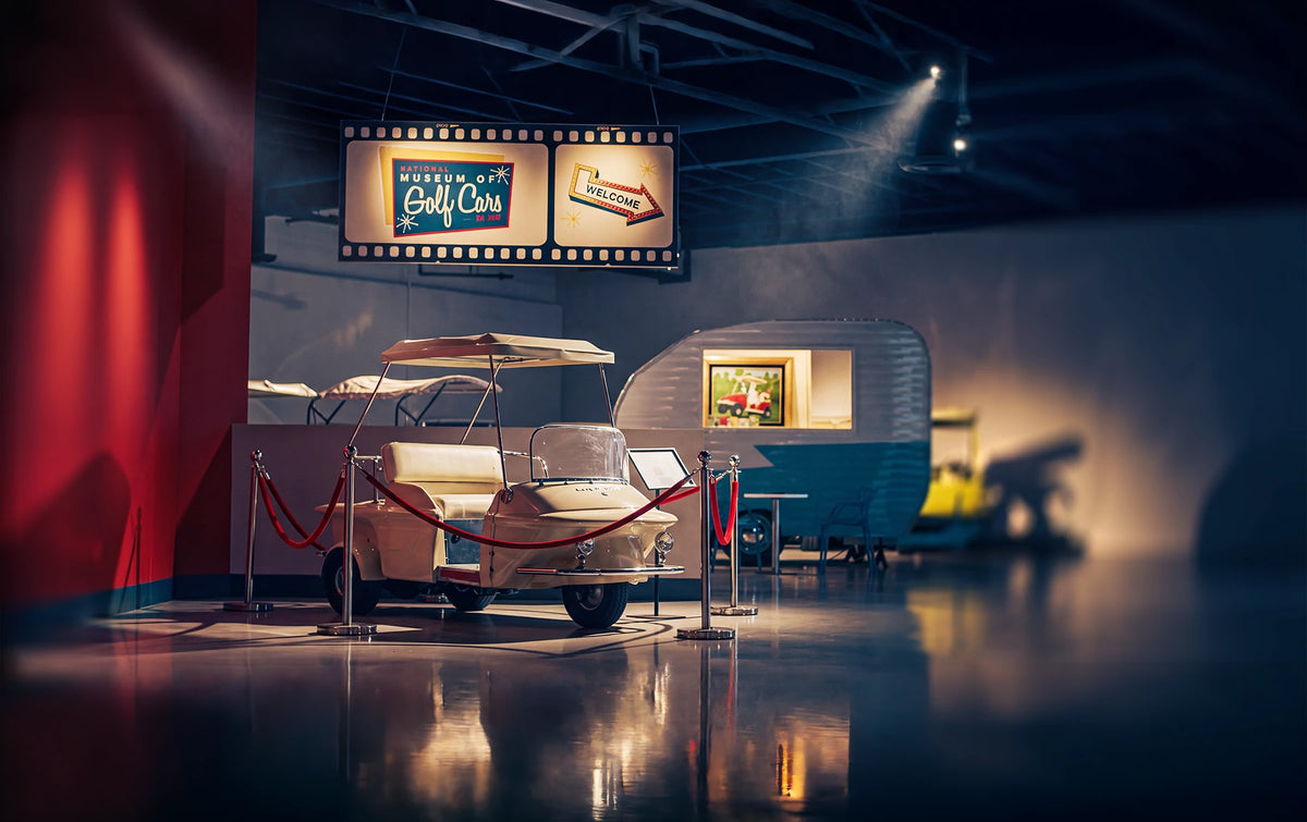 Historic golf car exhibit with illuminated National Museum of Golf Cars sign
